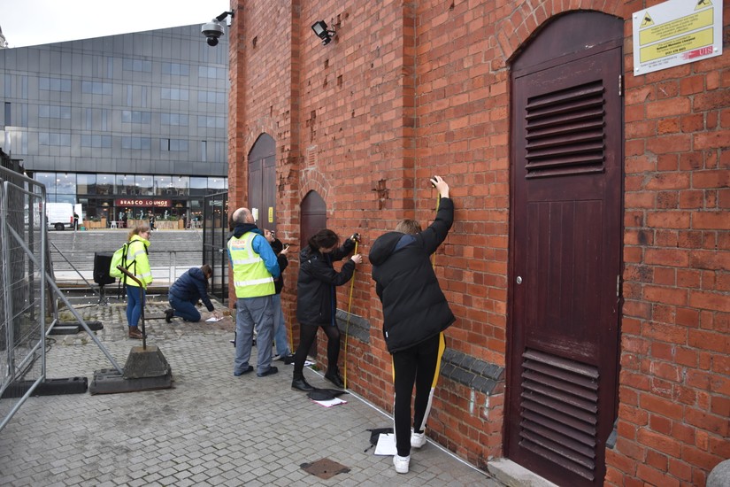 Emerging archaeologists recording wartime damage to the side of the GWR building